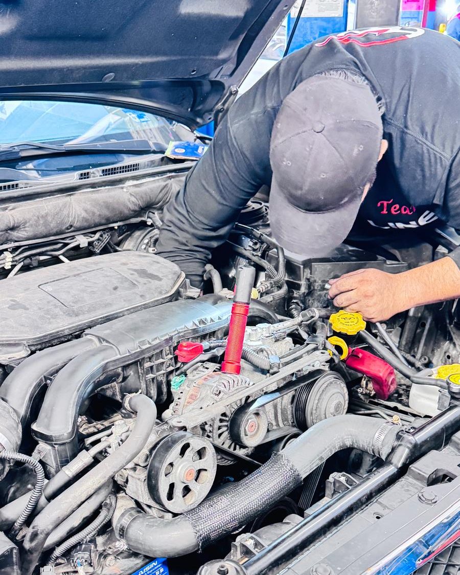 A Frontline Auto Plus technician working under the hood of a customer car