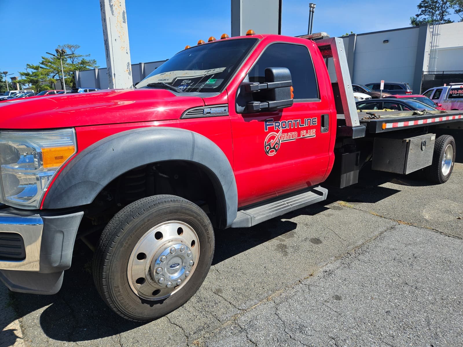 The red Frontline Auto Plus flatbed tow truck